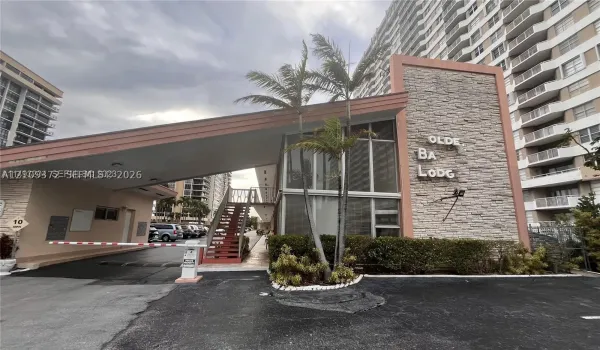 Covered porte-cochere entry, stacked stone exterior facade, floor-to-ceiling windows, and motorized security gate