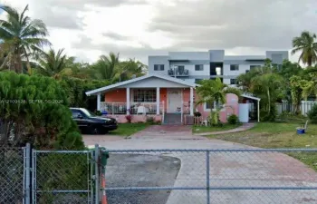 Single-story residence featuring a covered front porch, concrete driveway, and chain-link perimeter fencing