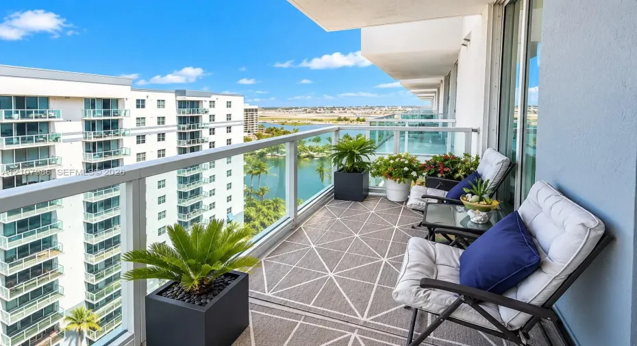 Covered balcony featuring a glass panel railing, concrete flooring, and water scenery