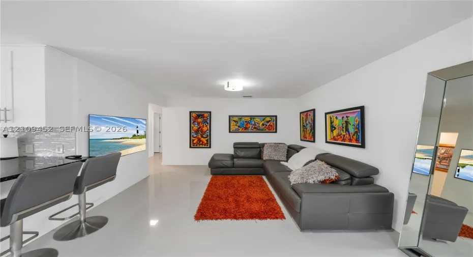 Interior featuring large-format tile flooring, kitchen peninsula with dark stone countertop, and mosaic glass tile backsplash