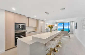 A stunning designer kitchen featuring sleek contemporary cabinetry, premium finishes, and an expansive island, perfectly complemented by breathtaking ocean views.