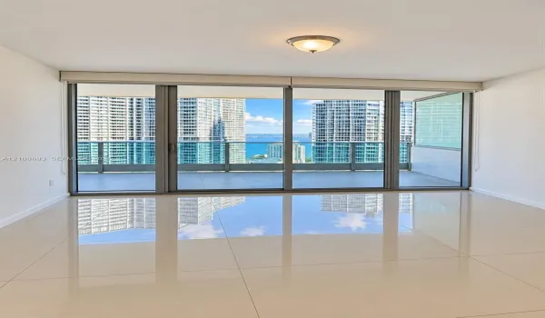 Floor-to-ceiling sliding glass doors, expansive covered balcony, polished tile flooring, and flush-mount lighting