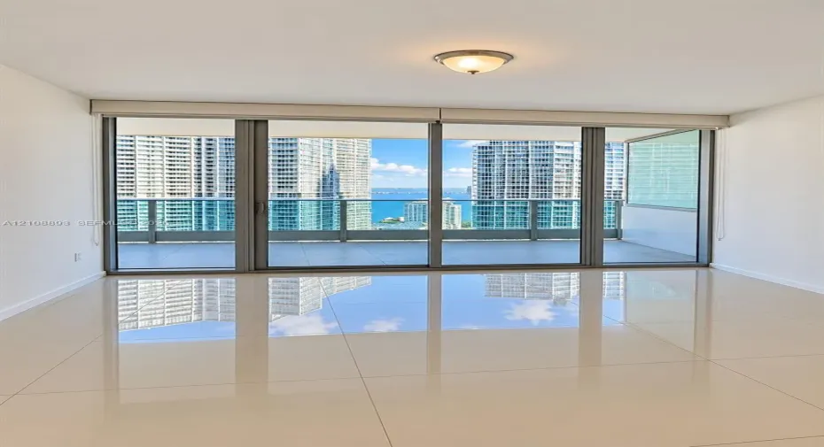 Floor-to-ceiling sliding glass doors, expansive covered balcony, polished tile flooring, and flush-mount lighting