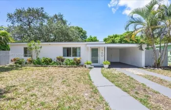 Single-story residence featuring a stucco exterior, attached carport, concrete driveway, and mature landscaping