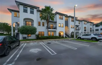 Multi-story stucco exterior with arched architectural details, private balconies, and dedicated surface parking