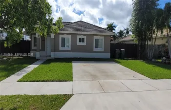 Single-story residence with a concrete tile roof, neutral stucco exterior, covered entryway, concrete driveway, and landscaped lawn
