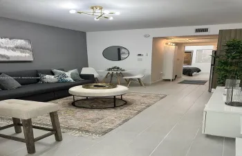 Interior space featuring light-toned tile flooring, a gold-finish geometric multi-light fixture, and a bold grey accent wall