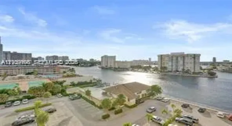 High-rise perspective featuring panoramic water frontage, palm landscaping, and urban skyline horizon
