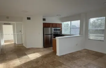 Kitchen featuring stainless steel appliances, wood cabinetry, stone-finish tile flooring, and recessed lighting