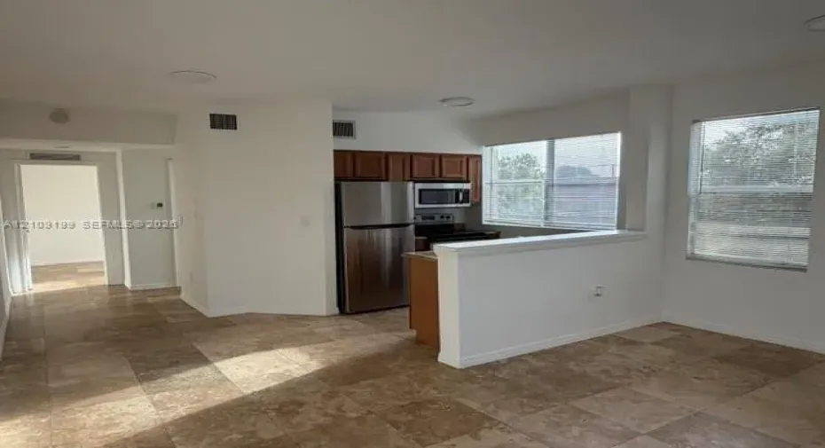 Kitchen featuring stainless steel appliances, wood cabinetry, stone-finish tile flooring, and recessed lighting