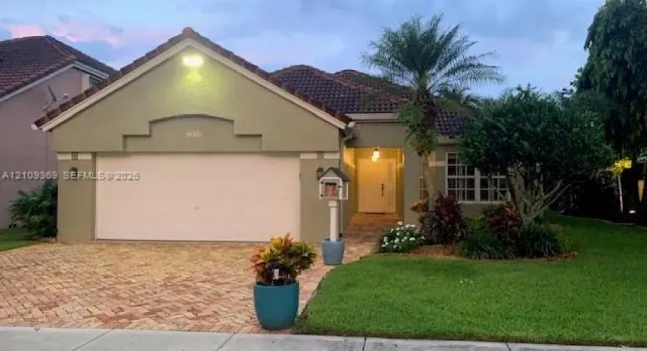 Single-story exterior featuring a paver driveway, tiled roof, decorative gable detailing, and a multi-pane window