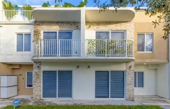 Multi-level exterior featuring stacked stone veneer, private upper-level balcony with metal railings, and dual-level sliding glass doors