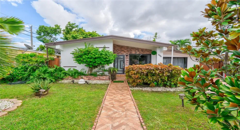 Mid-century modern architectural style featuring a low-pitched roofline, stone veneer facade accent, and a dedicated herringbone-patterned paved walkway