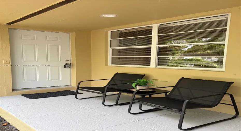Covered entryway featuring a painted concrete floor, a six-panel entry door, and multi-pane window with white framing and recessed ceiling lighting