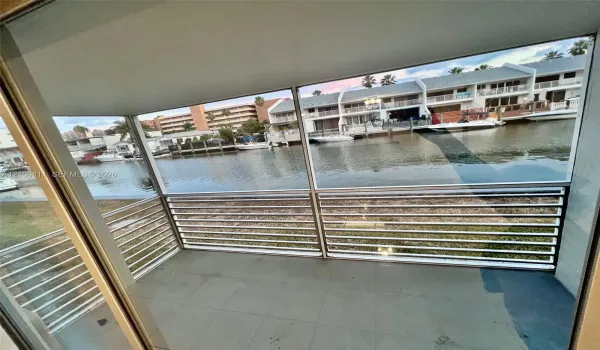 Covered balcony featuring tile flooring and horizontal metal railings overlooking a canal with bulkhead docks