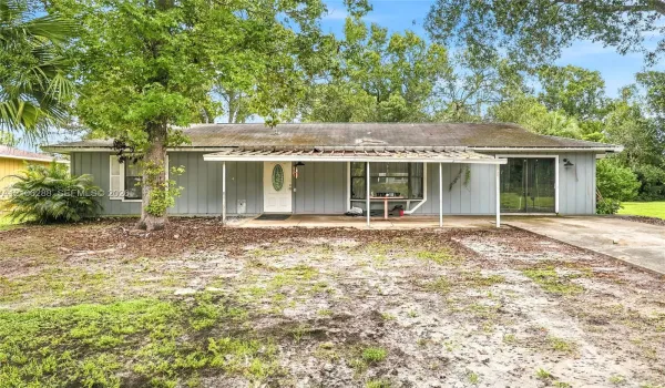 Single-story exterior featuring light-toned vertical siding, a covered front porch, a bay window, and a concrete driveway