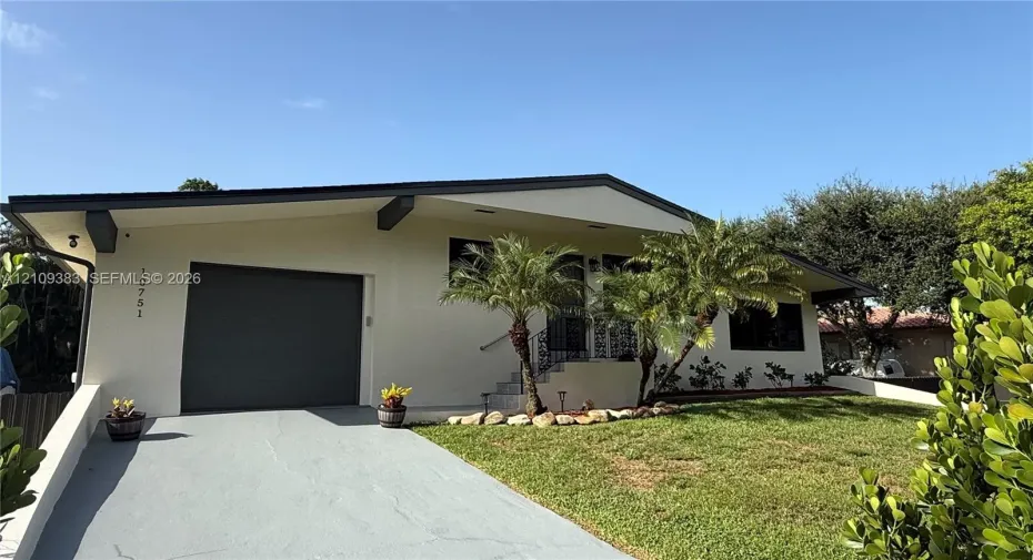 Mid-century modern exterior featuring low-pitched rooflines, exposed support beams, integrated single-car garage, and desert-inspired landscape accents