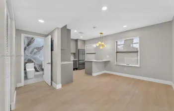 Open-concept interior featuring light wood-finish flooring, recessed lighting, a kitchen peninsula with integrated counter seating, and a modern multi-globe chandelier