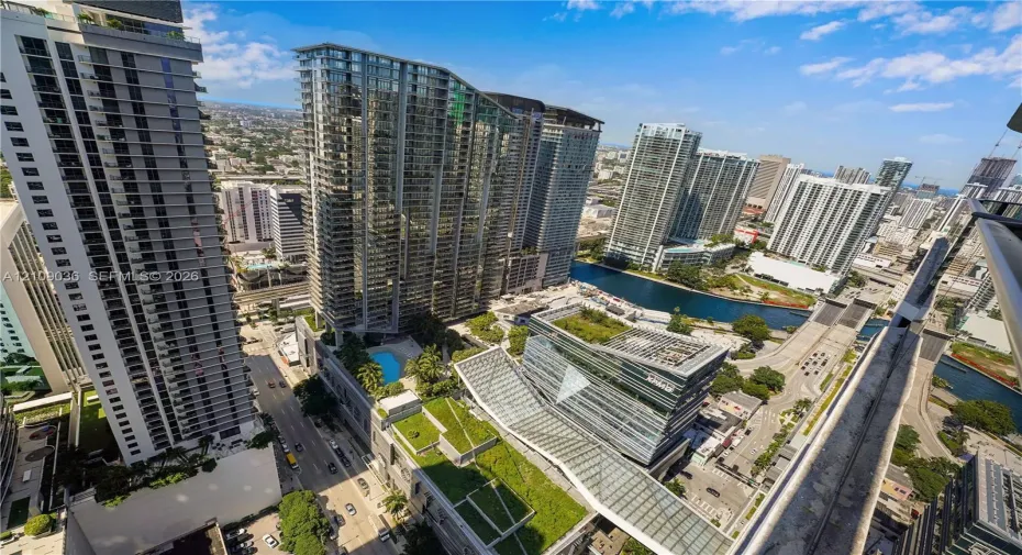 High-rise perspective featuring an outdoor swimming pool, landscaped green roofs, glass-facade architecture, and water frontage
