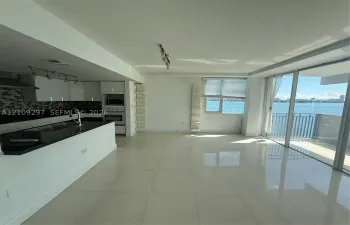 Kitchen featuring white cabinetry, dark countertops, a tiled backsplash, and built-in stainless steel oven, finished with large-format tile flooring and floor-to-ceiling glass sliding doors opening to an exterior balcony