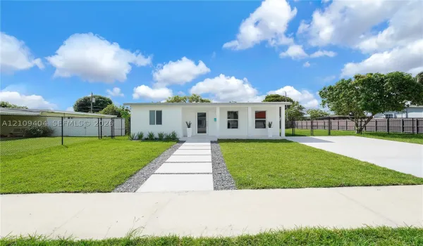 Single-story exterior featuring a covered front porch, concrete paver walkway, gravel landscaping, attached carport, and a concrete driveway