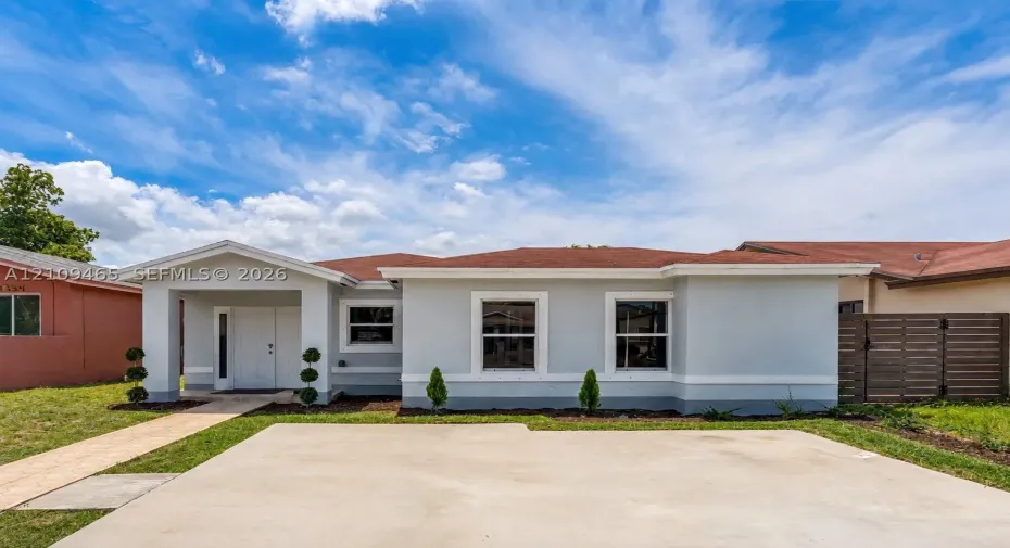 Single-story residence featuring a light-toned stucco exterior, asphalt shingle roof, double-entry front doors, concrete driveway, and a horizontal-slat privacy fence