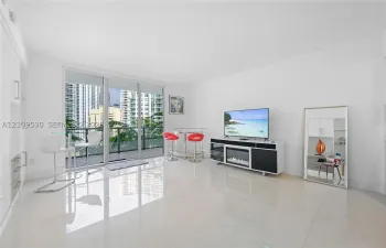 Living area featuring large-format tile flooring, floor-to-ceiling glass sliding doors, and built-in cabinetry