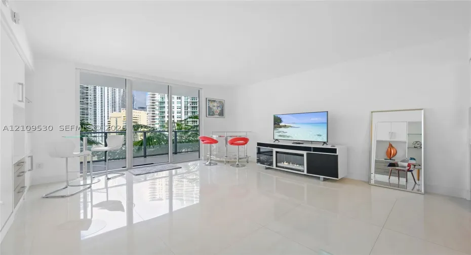 Living area featuring large-format tile flooring, floor-to-ceiling glass sliding doors, and built-in cabinetry