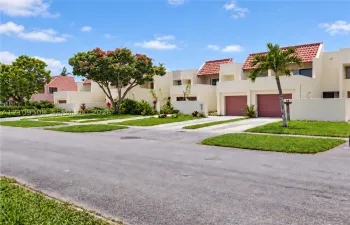Stucco exterior featuring red tile roof accents, integrated garages, and manicured landscaping