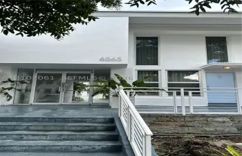 Modern building facade featuring large windows, a white railing, stone accents, and an entrance with glass​​‌​​​​‌​​‌‌​‌‌​​​‌‌​‌​‌​‌​​​‌​​ doors
