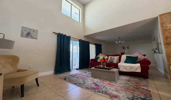 Vaulted ceiling, ceramic tile flooring, vertical sliding glass door, and multi-light chandelier