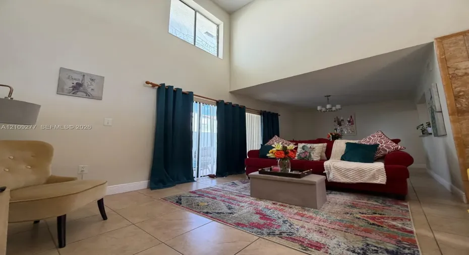 Vaulted ceiling, ceramic tile flooring, vertical sliding glass door, and multi-light chandelier