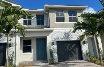 Two-story exterior featuring a stone veneer facade, integrated single-car garage, multi-pane windows, and a covered entryway with a solid-panel door