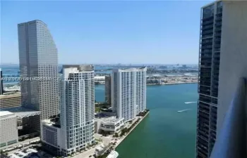 High-rise balcony featuring metal railing, panoramic water expanse, and urban skyline panorama