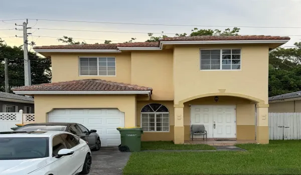 Two-story exterior featuring a stucco facade, clay tile roof, arched entryway, and attached single-car garage