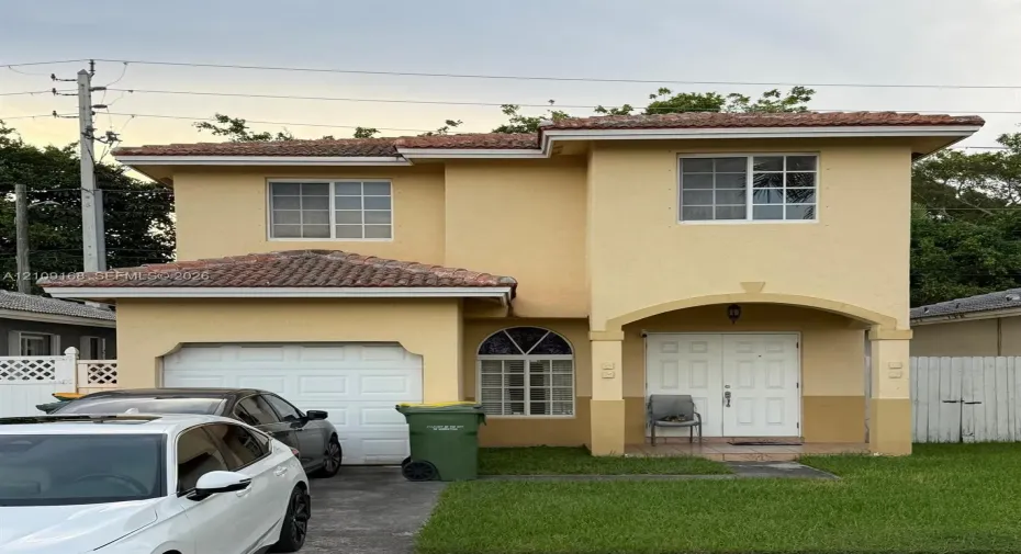 Two-story exterior featuring a stucco facade, clay tile roof, arched entryway, and attached single-car garage