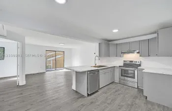 Kitchen featuring grey shaker-style cabinetry, stone-pattern countertops, stainless steel appliances, and wood-finish flooring