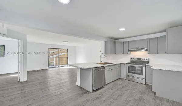 Kitchen featuring grey shaker-style cabinetry, stone-pattern countertops, stainless steel appliances, and wood-finish flooring