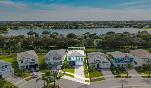 Two-story residence featuring a tile roof, paver driveway, attached two-car garage, and a waterfront lot location