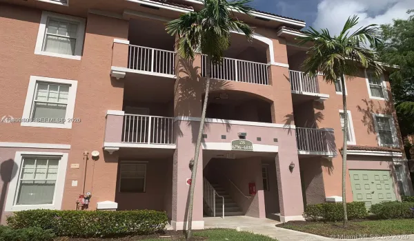 Stucco exterior featuring multi-level balconies with metal railings, arched architectural details, and mature palm landscaping