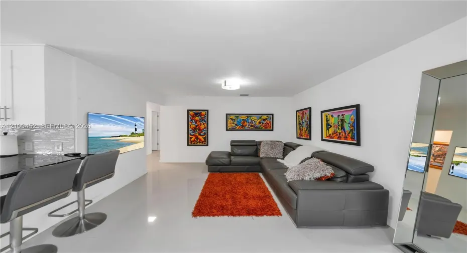 Interior featuring large-format tile flooring, kitchen peninsula with dark stone countertop, and mosaic glass tile backsplash