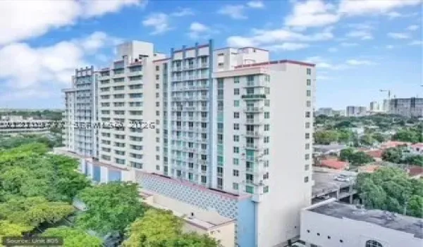 High-rise residential exterior featuring a multi-story facade, structured grid of private balconies, patterned architectural paneling, and integrated parking facility