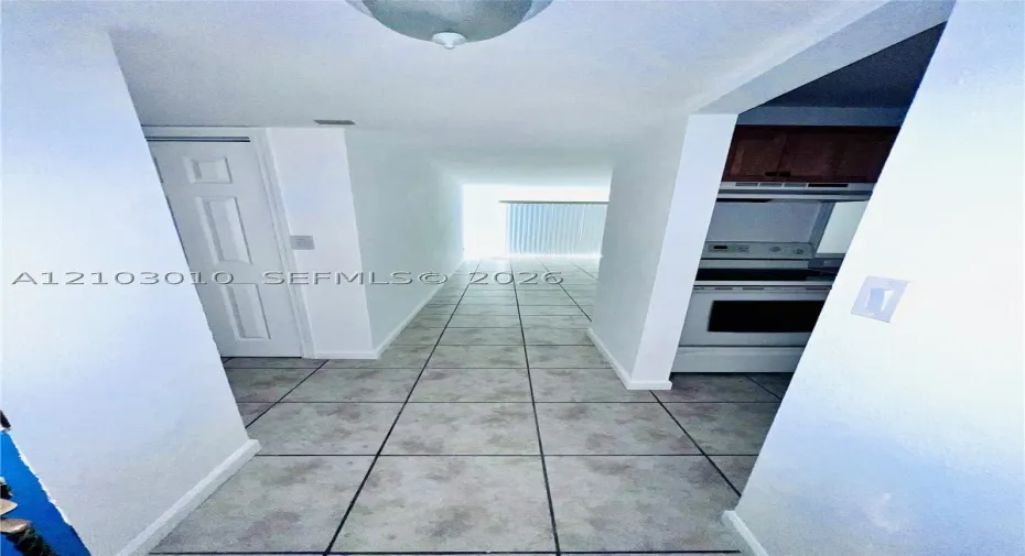 Tile flooring, ceiling-mounted light fixture, white interior doors, and built-in kitchen cabinetry