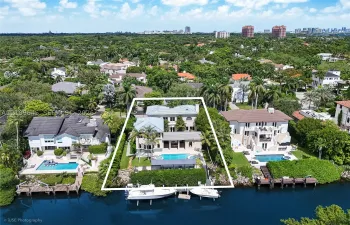 Waterfront property featuring a multi-story residence, private swimming pool, integrated spa, and a bulkhead-lined dock on a canal