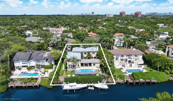Waterfront property featuring a multi-story residence, private swimming pool, integrated spa, and a bulkhead-lined dock on a canal