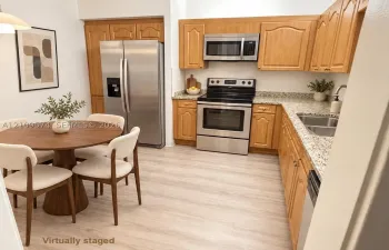 Staged Kitchen featuring wood cabinetry, stone-finish countertops, stainless steel appliances, and light-tone vinyl wood-finish flooring