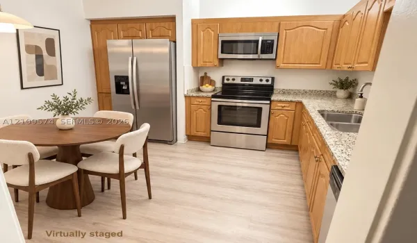 Staged Kitchen featuring wood cabinetry, stone-finish countertops, stainless steel appliances, and light-tone vinyl wood-finish flooring