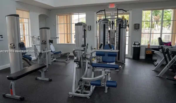 Fitness center featuring floor-to-ceiling multi-pane windows, high ceilings, and rubberized flooring