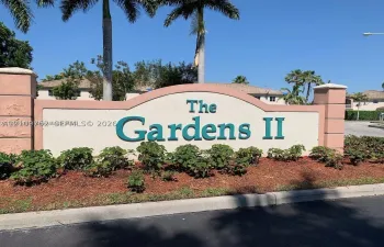 Stucco monument sign featuring arched masonry detailing and mature palm trees