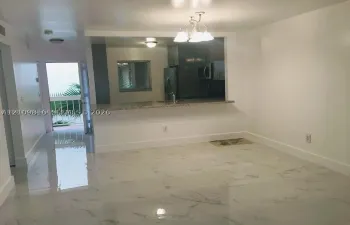 Large format polished tile flooring, kitchen featuring a stone-surface breakfast bar, and an overhead multi-light fixture